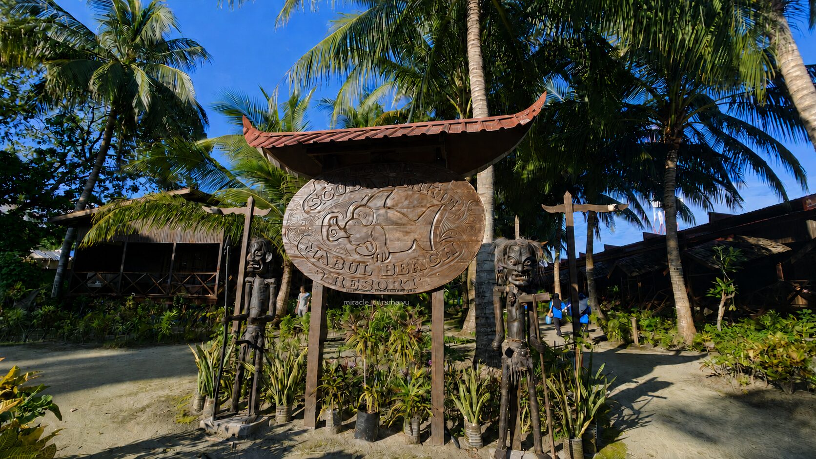 ヤシの木に囲まれたScuba Junkie Mabul Beach Resortの木製看板